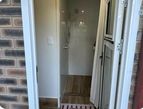 a shower with a glass door next to a brick wall at Mains Rd single room M6 in Brisbane