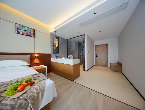 a bedroom with a bed with a tray of fruit on it at Leaf Hotel in Yantaiqian