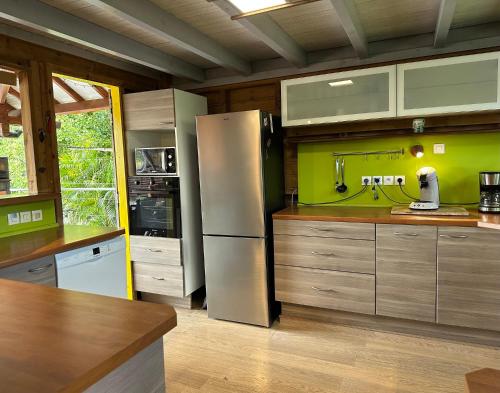 a kitchen with a stainless steel refrigerator and wooden cabinets at Villa Atypique - Charme & Confort in Le Moule