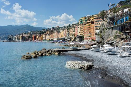 a beach with chairs and buildings in the water at Hotel Cenobio Dei Dogi in Camogli
