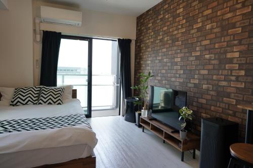 Cette chambre dispose d'un mur en briques, d'un lit et d'une télévision. dans l'établissement REVISION Kairouyama-tei - Vacation STAY 15801, à Hiroshima