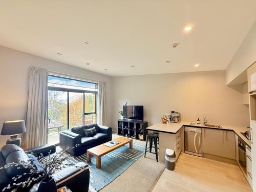 a living room with a couch a table and a kitchen at @MyHolidays - My Remarkable view in Queenstown