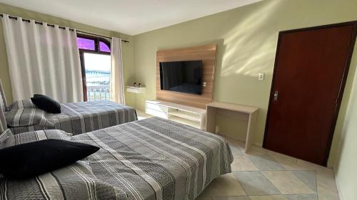 une chambre d'hôtel avec deux lits et une télévision à écran plat dans l'établissement Mirante LUZ FLORIPA, à Florianópolis