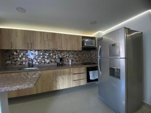 a kitchen with a stainless steel refrigerator and wooden cabinets at Estancia mágica al lado del cc fabricato in Bello