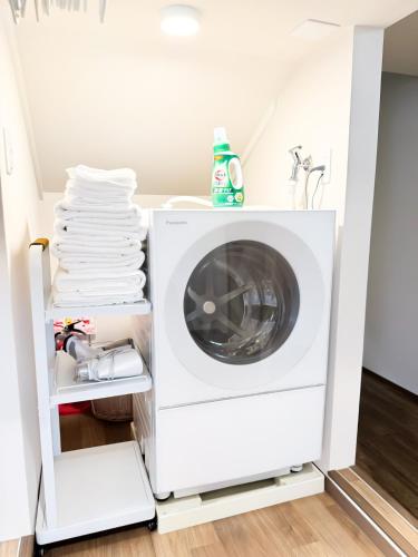 a washing machine in a laundry room with a stack of towels at Tsuruhashi 1F 9 min walk &3BR Apt for 6&Near Enba Natural Onsen&JR Direct to Namba, Nara & USJ in Osaka