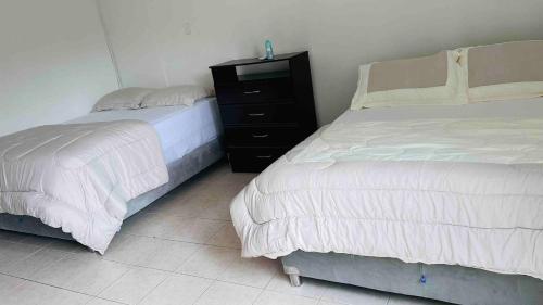 a bedroom with two beds and a black dresser at Casa a 2 minutos de la playa en playa mendoza in Tubará