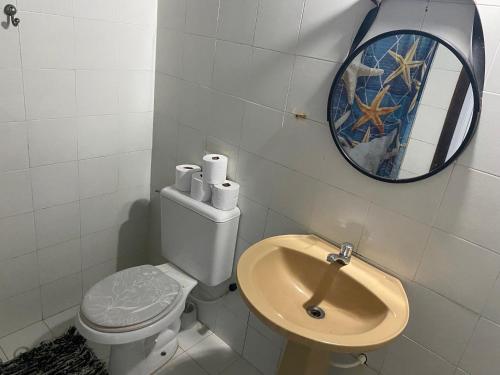 a bathroom with a toilet and a mirror and a sink at Bangalô Pontal do Atalaia com piscina para casal ou família in Arraial do Cabo