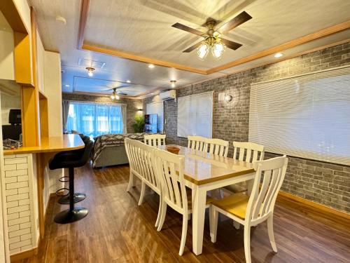 een eetkamer met een tafel, stoelen en een bank bij ヴィラ マイラニハウス沖縄 in Hamakawa