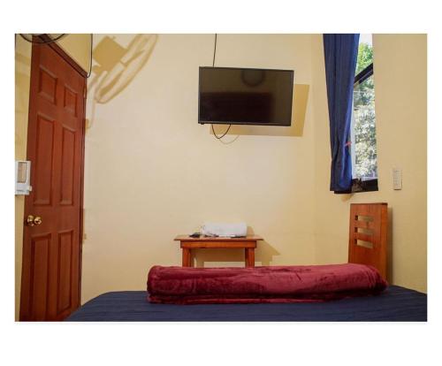 a room with a bed with a table and a tv at Casa Jhada-Xilitla in Xilitla