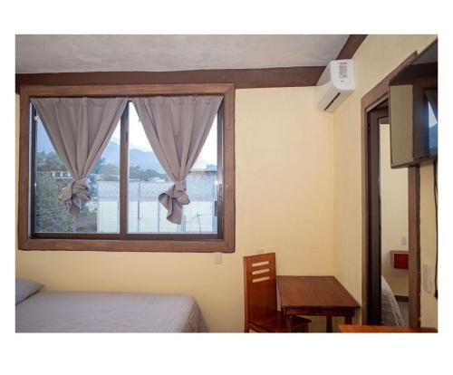 a bedroom with a window with a table and a bed at Casa Jhada-Xilitla in Xilitla