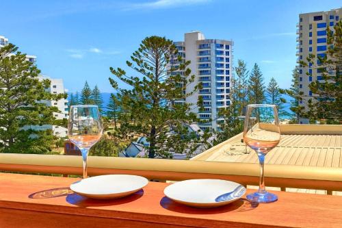 CoolangattaにあるSnapper Rocks Ocean view Retreatのバルコニーにテーブルとワイン2杯