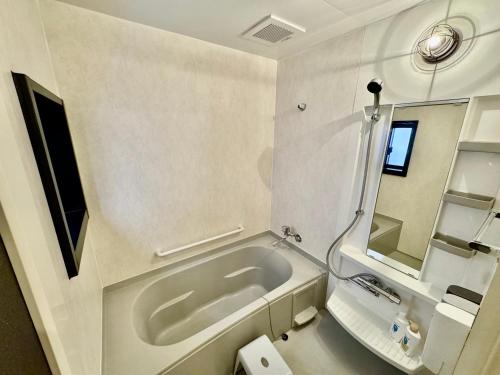 een witte badkamer met een bad en een spiegel bij ヴィラ マイラニハウス沖縄 in Hamakawa