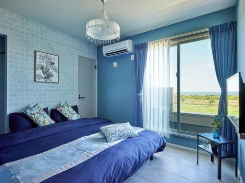 a blue bedroom with a bed and a window at VOGUE C, a private inn with a panoramic view of th - Vacation STAY 14693v in Isumi