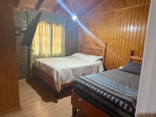 a bedroom with two beds in a wooden room at Hotel Chehueque in Vallenar