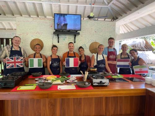 um grupo de pessoas em pé ao redor de uma mesa com suas bandeiras em Anggrek Putih Cooking Class & Guest House em Senggigi