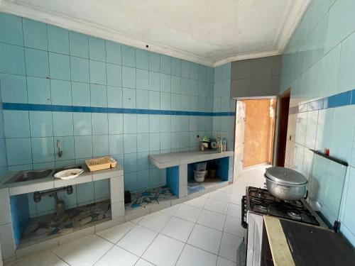 a blue tiled kitchen with a sink and a stove at Résidence HSN in Cococodji