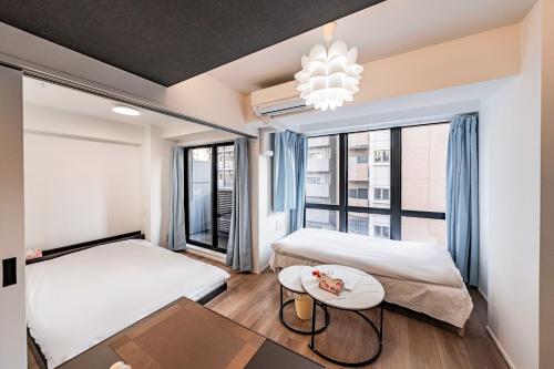 大阪Namba River Side Garden Hotel的一间卧室，有两张床、一张桌子和一扇窗户