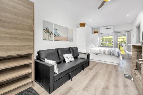 Una sala de estar con un sofá negro y una cama. en Vita Resort Vernon - Modern Studio on Okanagan Lake, en Vernon