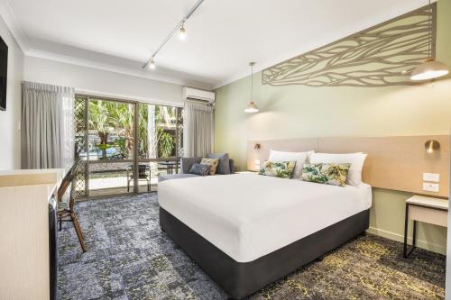 a bedroom with a large bed and a balcony at Nightcap at Kondari Resort in Hervey Bay