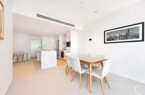 une salle à manger avec des murs blancs et une table et des chaises en bois dans l'établissement L19 Spacious Apt, Wi-Fi, Parking by Stylish Stays, à Brisbane