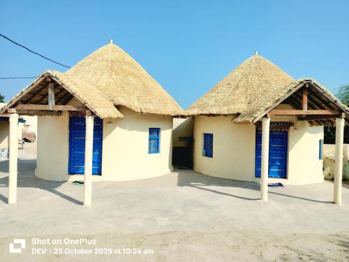 a group of three houses with thatched roofs at Ranfamily home stay in Dhordo