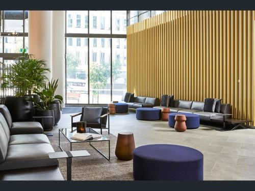 a lobby with couches and chairs in a building at LvL29 Rooftop Pool Carpark Netflix by Stylish Stays in Brisbane