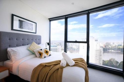 a bedroom with a white bed with large windows at Lvl30 Garden/River views Balcony by Stylish Stays in Brisbane