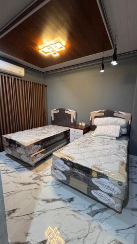two beds in a room with marble floors at MH Villa Deluxe Twin in Pancor