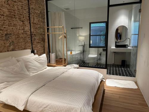 a bedroom with a large white bed and a bathroom at The Heritage 1937 in Kuching