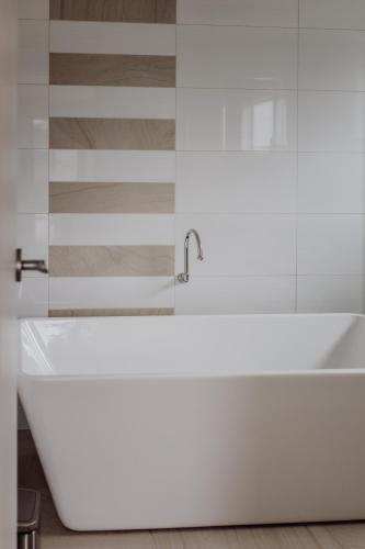 a white bathtub in a bathroom with a striped wall at Bicheno Gardens in Bicheno