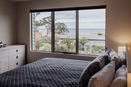 a bedroom with a bed and a large window at Bicheno Gardens in Bicheno