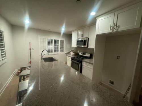 a kitchen with white cabinets and a granite counter top at Soulistic Vibes Normandie in Los Angeles