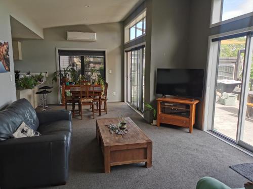 a living room with a couch and a tv and a table at Apartment style Beach House. Birdlings Flat in Little River