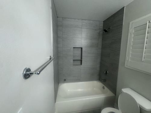 a white bathroom with a tub and a toilet at Soulistic Vibes Normandie in Los Angeles