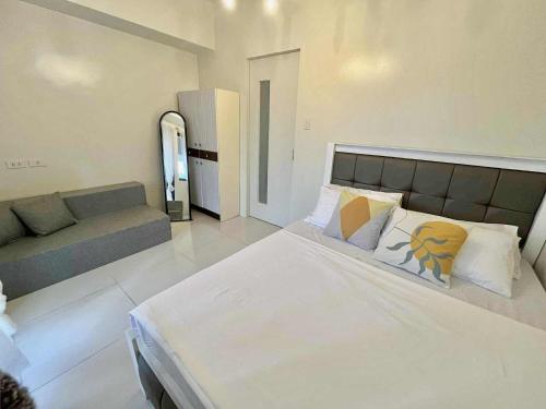 a bedroom with a large bed and a couch at 1BR with Balcony Cool Breeze Morning Sun by Cherisia's Hideaway in Baguio
