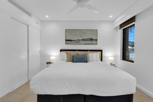 una camera da letto con un grande letto bianco con due lampade di Infinity's Edge - Poolside Retreat at Temple Resort a Craiglie