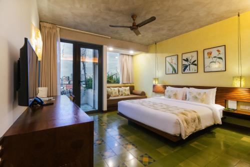 a bedroom with a bed and a television and a couch at Penh House Hotel in Phnom Penh