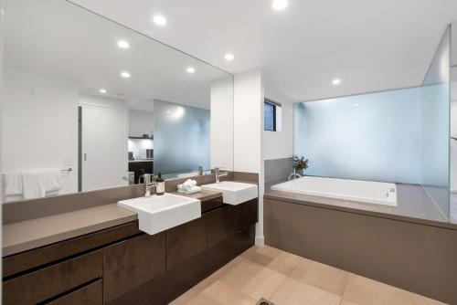 un bagno con due lavandini e un grande specchio di Infinity's Edge - Poolside Retreat at Temple Resort a Craiglie