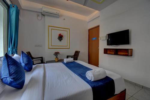 ein Schlafzimmer mit einem großen Bett mit blauen Kissen und einem TV in der Unterkunft Sai palace inn 2 bhk furnished flat in Dāpuri