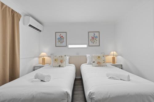 2 camas en una habitación con paredes blancas y 2 lámparas en Central, Comfortable, Convenient - CCC, en Pialba