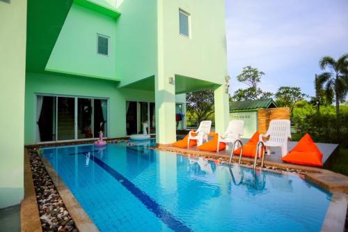 une piscine avec des chaises orange et blanches à côté d'un bâtiment dans l'établissement The Green House Pool Villa Udonthani, à Ban Ngoi