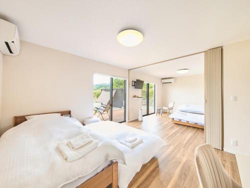 een witte slaapkamer met een groot bed en een balkon bij Awaji Nature Retreat in Awaji