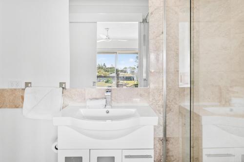 a white bathroom with a sink and a shower at Isle Of Palms Resort in Gold Coast