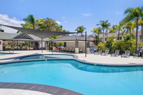 a large swimming pool with chairs and umbrellas at Isle Of Palms Resort in Gold Coast