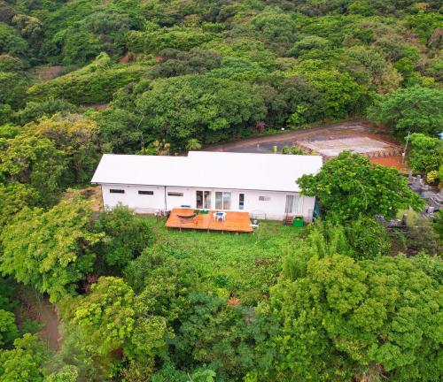une vue aérienne d'un bâtiment blanc dans une forêt dans l'établissement 奄美ゲストハウス sou 海と森のテラス 2025年夏オープン, à Tatsugo