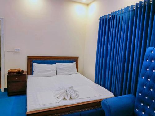 a bedroom with a bed with blue drapes at Perfect Lodge Guest House in Islamabad