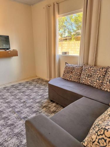 Una sala de estar con un sofá y una ventana. en Refujo Ideal em Família, en Prado