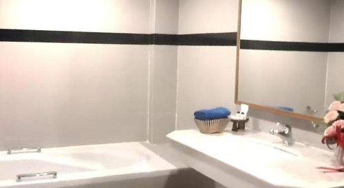 une salle de bain blanche avec un lavabo et un miroir dans l'établissement PC Palace Hotel, à Sakon Nakhon