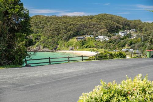 an empty road next to a beach with a fence at Seascape in Seal Rocks