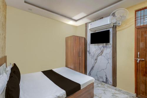 a bedroom with a bed and a tv and a window at Hotel O Daraganj Ghat Prayagraj Formerly Purohit Inn in Colonelganj